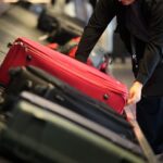 Reisende am Gepäckband, symbolisieren Unsicherheiten durch neue Wehrpflichtregelung und Reisedokumentation.