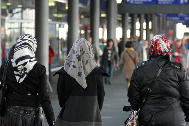 Mehrere Frauen mit Kopftüchern auf einer belebten Straße, symbolisierend kulturelle Diversität in Europa.