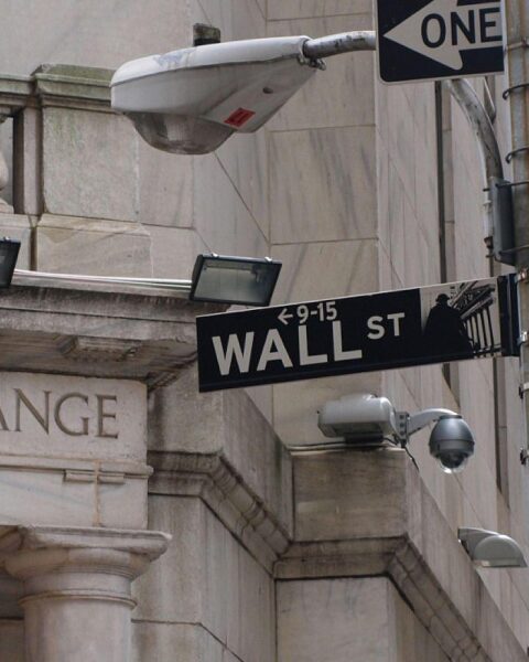 Wallstreet mit steigenden Indizes, beeindruckende Gebäude, Handel, Finanzaktivität und positive Marktstimmung.