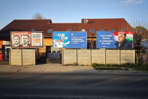 Wahlplakate und Menschen vor Wahllokalen in Budapest zur Parlamentswahl 2026.