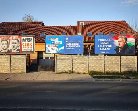 Wahlplakate und Menschen vor Wahllokalen in Budapest zur Parlamentswahl 2026.