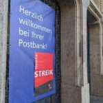 Streik-Hinweis an Postbank-Filiale, symbolisiert Forderungen nach besseren Arbeitsbedingungen und Gehältern.