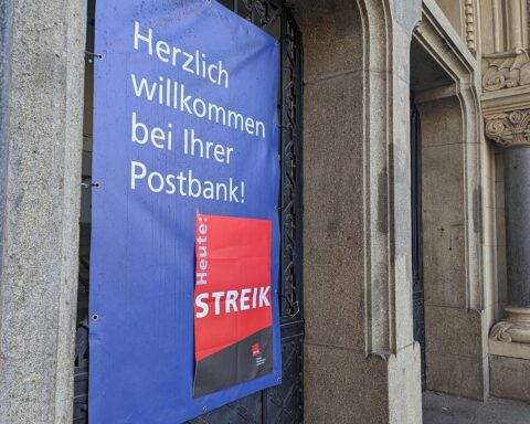 Streik-Hinweis an Postbank-Filiale, symbolisiert Forderungen nach besseren Arbeitsbedingungen und Gehältern.