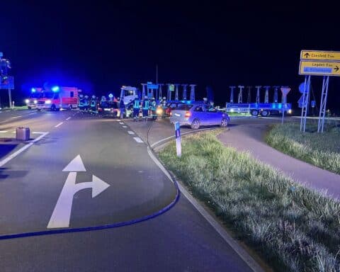 Verkehrsunfall mit mehreren Verletzten auf belebter Straße, Rettungswagen und Polizeipräsenz sichtbar.