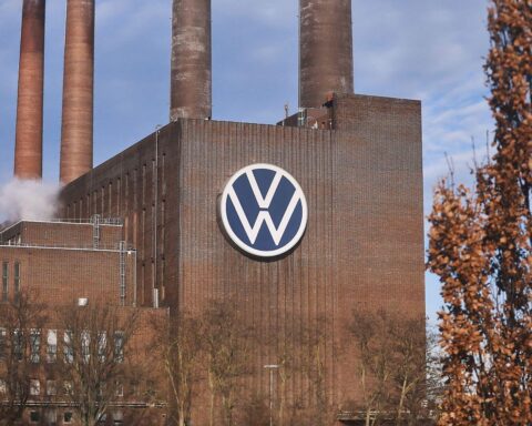 Volkswagen-Werk mit Autos, Umsatz-Statistiken und rückläufigem Absatz im Hintergrund.