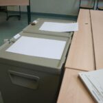 Wahllokal mit Wahlurnen und Wählern, Darstellung der aktuellen Wahlbeteiligung in Freiburg.