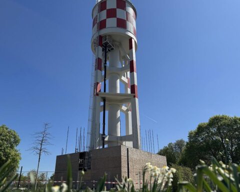 Fertig sanierter Wasserturm in Neu-Ulm, strahlt markante weiß-rote Farbe unter blauem Himmel.