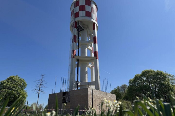 Fertig sanierter Wasserturm in Neu-Ulm, strahlt markante weiß-rote Farbe unter blauem Himmel.