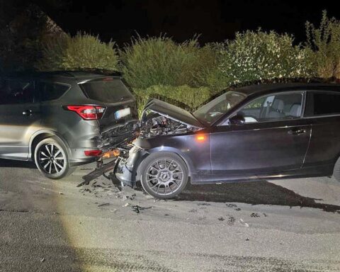 Unfallort mit beschädigten Fahrzeugen, Polizei und Fahndung nach alkoholisiertem Fahrer.