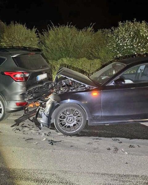 Unfallort mit beschädigten Fahrzeugen, Polizei und Fahndung nach alkoholisiertem Fahrer.
