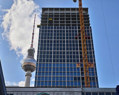 Baustelle in Berlin mit Fernsehturm, sonnigem Himmel und Baustellenarbeiten im Vordergrund.