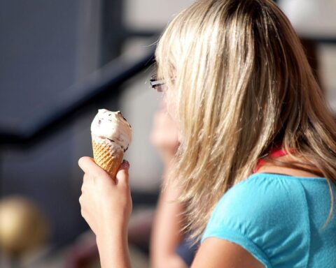 Frau genießt Eiscreme an einem sonnigen Tag, symbolisiert warmes Wetter in Rheinland-Pfalz.