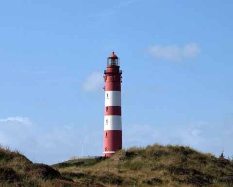 Leuchtturm im Sonnenschein vor blauem Himmel, symbolisiert mildes Wetter in Norddeutschland.
