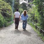 Ein Paar spaziert bei sonnigem Wetter in Thüringen, umgeben von grüner Landschaft.