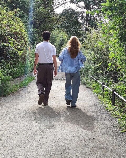 Ein Paar spaziert bei sonnigem Wetter in Thüringen, umgeben von grüner Landschaft.