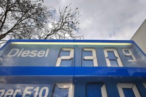 Spritpreise bleiben hoch; Tankstelle mit Preisanzeige und wartenden Fahrzeugen zeigt aktuelle Situation.
