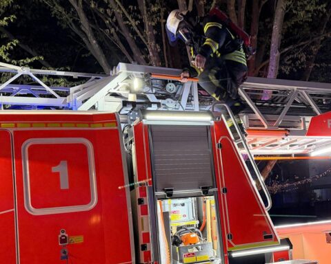 Drehleiter der Feuerwehr an Mehrfamilienhaus, Rauchzeichen, Einsatzkräfte im Aktion.