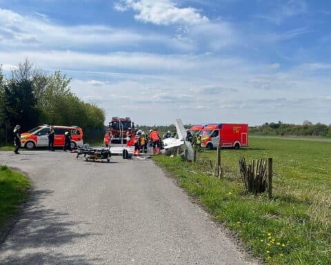 Ein abgestürztes Kleinflugzeug auf Wiese, Rettungskräfte, verletzte Personen, abgesperrte Umgebung.