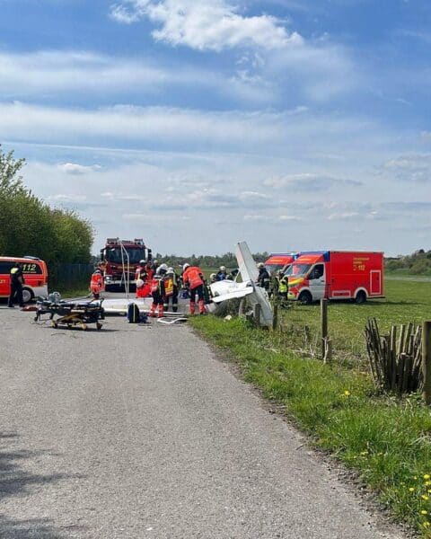 Ein abgestürztes Kleinflugzeug auf Wiese, Rettungskräfte, verletzte Personen, abgesperrte Umgebung.