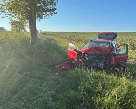Verunfallter Peugeot nach frontalem Aufprall gegen Baum, Feuerwehr löscht brennendes Fahrzeug.