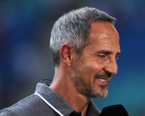 Adi Hütter, Eintracht Frankfurt Trainer, jubelnd auf dem Spielfeld, umgeben von Spielern und Fans.