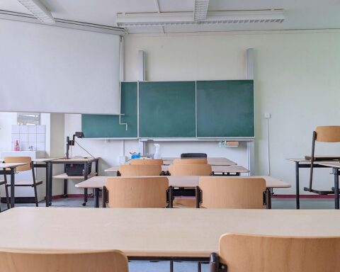 Ein moderner Klassenraum mit Technologie, Lehrer und Schüler, die Künstliche Intelligenz nutzen.
