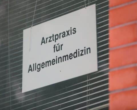 Ärzte in Praxis, besorgte Gesichter, Diskussion über Gesundheitspolitik und GKV-Einsparungen.