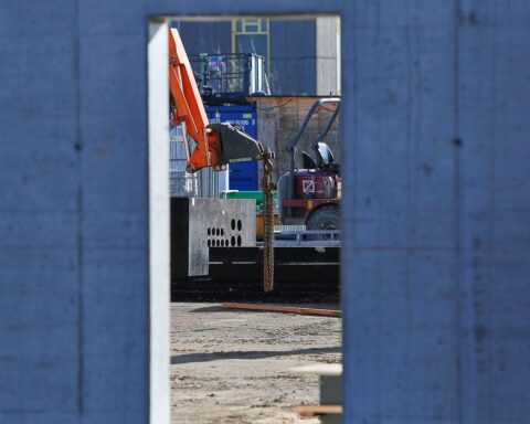Baustelle mit Bauarbeitern, Maschinen, unvollendeten Projekten und einem Banner für Infrastrukturverbesserungen.