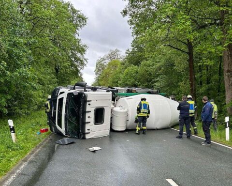 Umgekippter Betonmischer blockiert Landstraße, frischer Beton fließt in den Straßengraben.