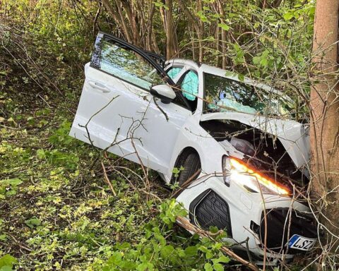 Unfallstelle mit beschädigtem Audi, Polizei vor Ort, medizinische Versorgung verletzter Passagiere.