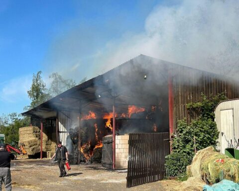 Löscharbeiten an brennender Lagerhalle mit Heuballen, Feuerwehr im Einsatz, keine Verletzten.