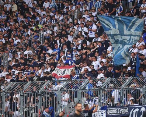 Fans von Hertha BSC feiern die Ankunft im Bahnhof, Polizeikräfte sichern die Veranstaltung.