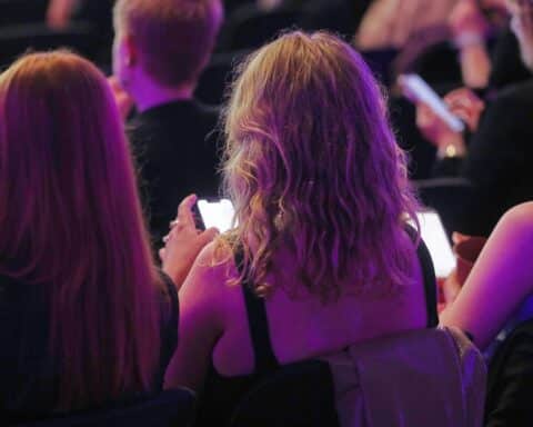 Junge Menschen interagieren mit Smartphones, symbolisieren digitale Teilhabe und Herausforderungen in sozialen Medien.
