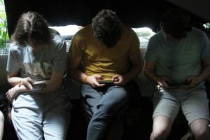 Junge Leute nutzen Smartphones, während sie über die Risiken von Social Media diskutieren.