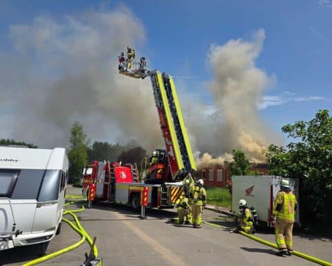 Feuerwehr löscht Dachstuhlbrand, große Rauchwolken, Einsatzkräfte mit Ausrüstung, stillgelegtes Nato-Gelände, Photovoltaikanlage.
