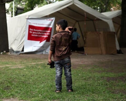 Flüchtlinge warten an einer Aufnahmestelle in Deutschland, symbolisieren Schutzsuchende und Integration.
