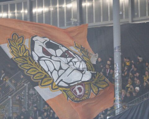 Dynamo-Fans feiern im Stadion, Polizei überwacht friedliche Stimmung während des Spiels.