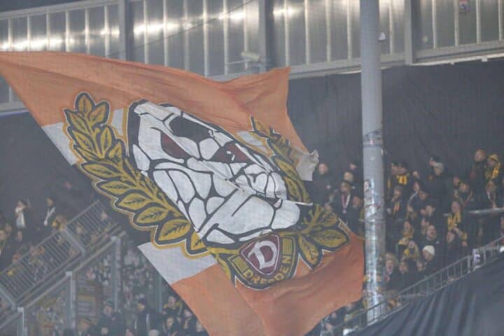 Dynamo-Fans feiern im Stadion, Polizei überwacht friedliche Stimmung während des Spiels.