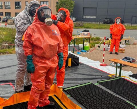 Feuerwehrkräfte im Einsatz, Schutzanzüge um unbekannten Stoff im Gewerbegebiet zu untersuchen.