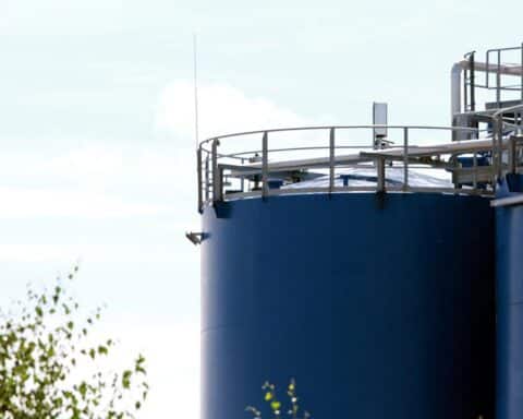 Öltanks vor einem sunset-ähnlichen Hintergrund, symbolisieren steigende Energiepreise und wirtschaftliche Unsicherheit.