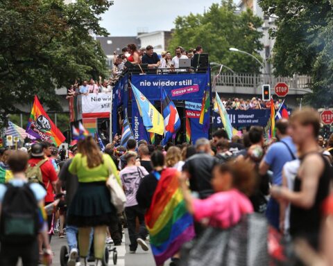 Bunte Parade mit Teilnehmern, Regenbogenflaggen und demonstrativer Vielfalt am Christopher Street Day.