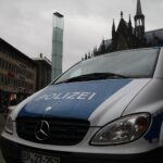 Polizeiauto vor Kölner Dom symbolisiert Forderung nach mehr Sicherheit an Bahnhöfen.
