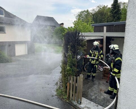 Feuerwehr bei Heckenbrand, Anwohner löschen selbst, Kontrolle mit Wärmebildkamera, Einsatzkräfte vor Ort.