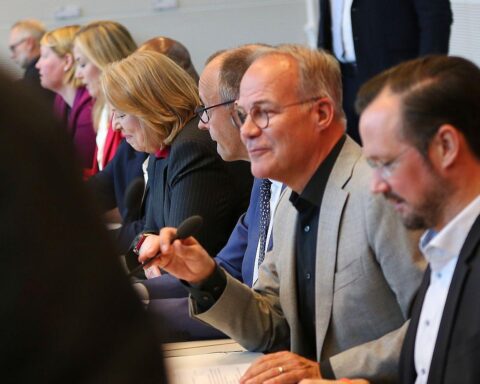 Friedrich Merz diskutiert mit SPD-Vertretern, während Uli Hoeneß die Regierungsarbeit kritisiert.
