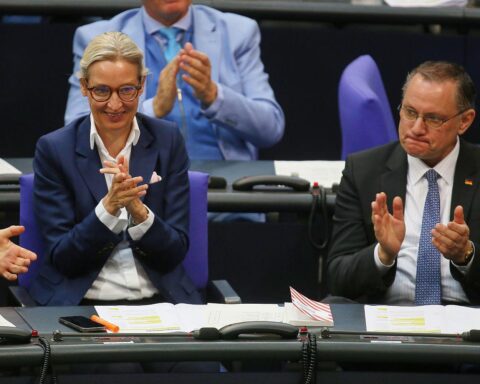 AfD-Politiker Alice Weidel und Tino Chrupalla diskutieren, während Umfragewerte veröffentlicht werden.