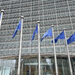 EU-Fahnen symbolisieren Zusammenarbeit, während geopolitische Unsicherheiten und Energiewende Herausforderungen darstellen.