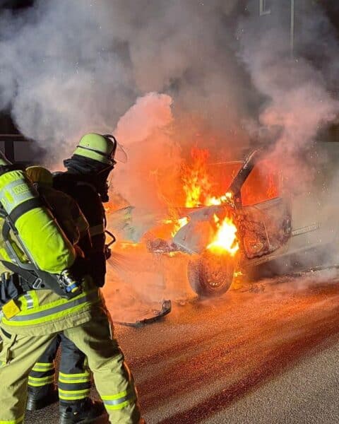 Brennender Kleintransporter am Fahrbahnrand, Feuerwehr im Einsatz mit Löschschaum.