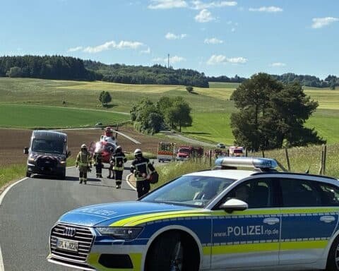 Unfallstelle mit beschädigten Fahrzeugen und Rettungskräften, die bei den Rettungsmaßnahmen helfen.