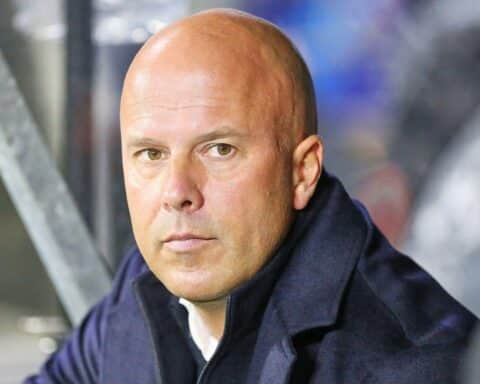 Arne Slot, ehemaliger Liverpool-Trainer, lächelnd im Stadion, reflektiert über seine Erfolge.