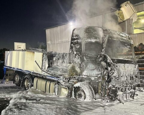 Lkw-Brand an einer Firma, Feuerwehr im Einsatz, Rauch und ausgebrannte Fahrzeugreste sichtbar.